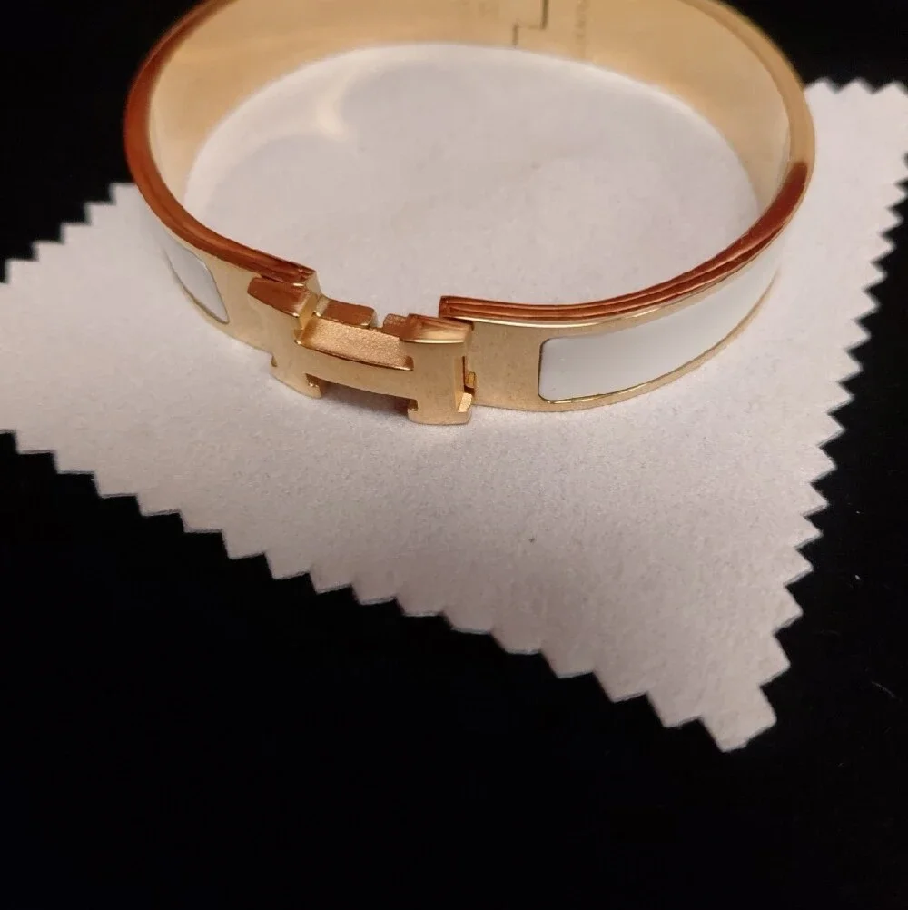 HERMES Gold and White Enamel Click H Bracelet with Signature H Accent.